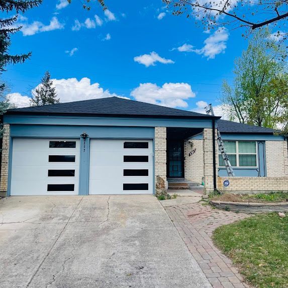 A house with two garage doors and a ladder in front of it.