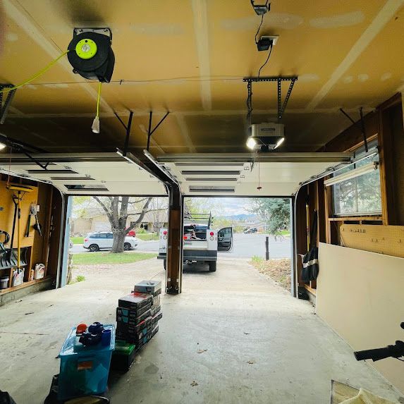 A garage with the door open and a tape measure hanging from the ceiling