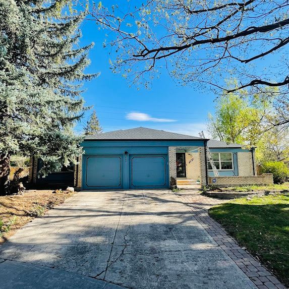 A house with a blue garage door and a brick driveway.