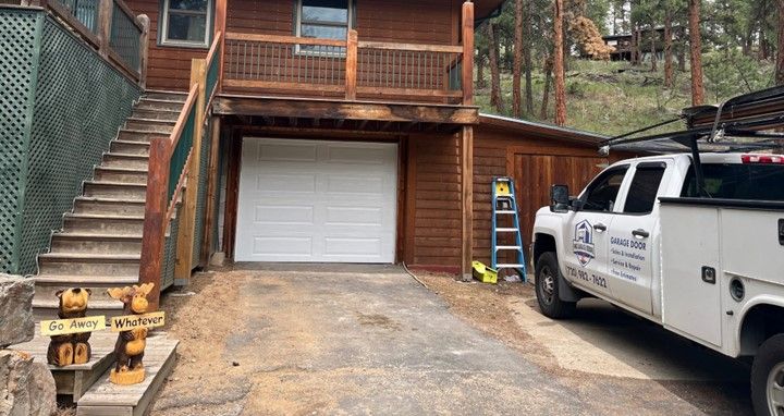 A white truck is parked in front of a wooden house.