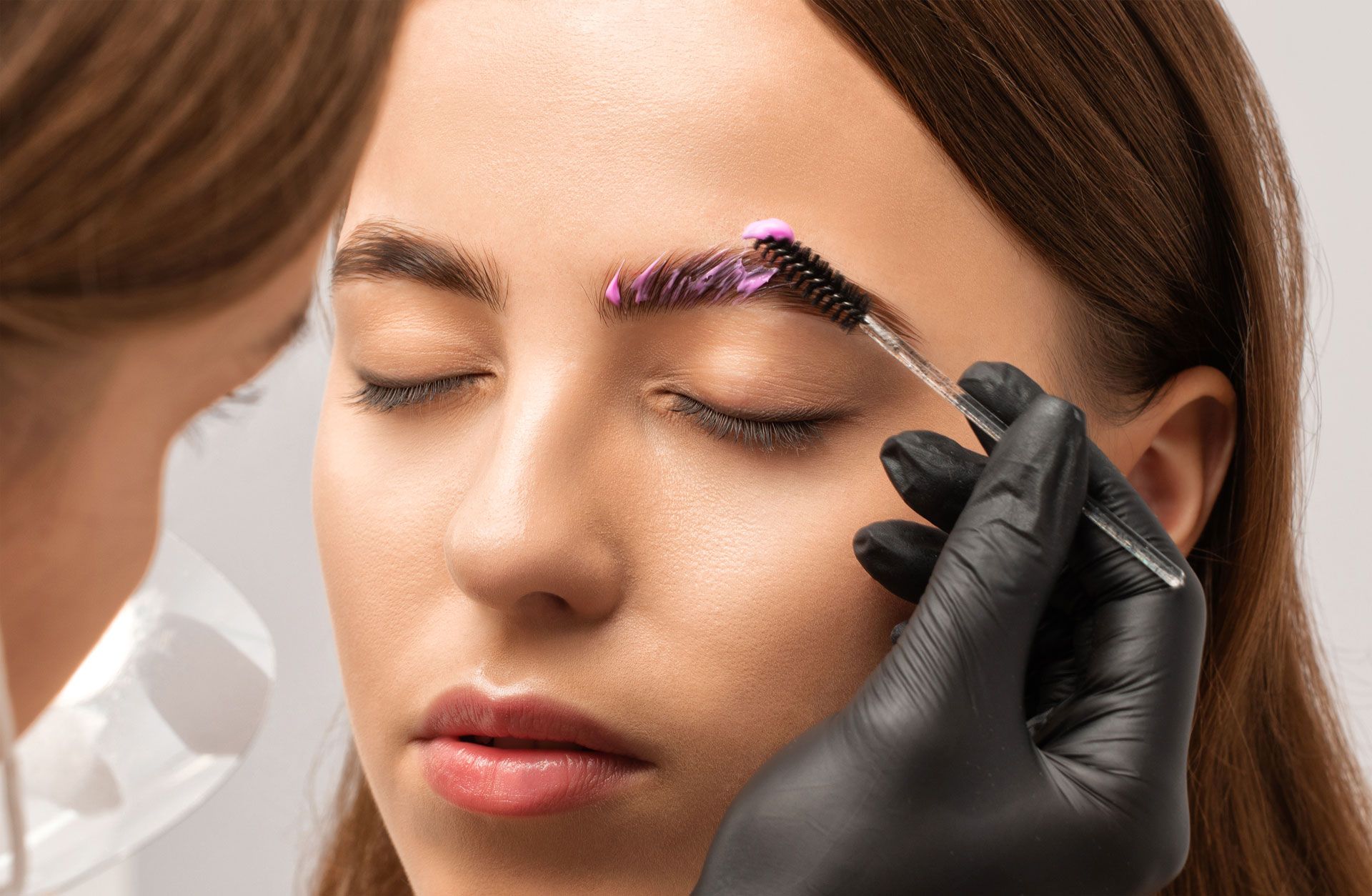 A woman is getting her eyebrows dyed in a salon