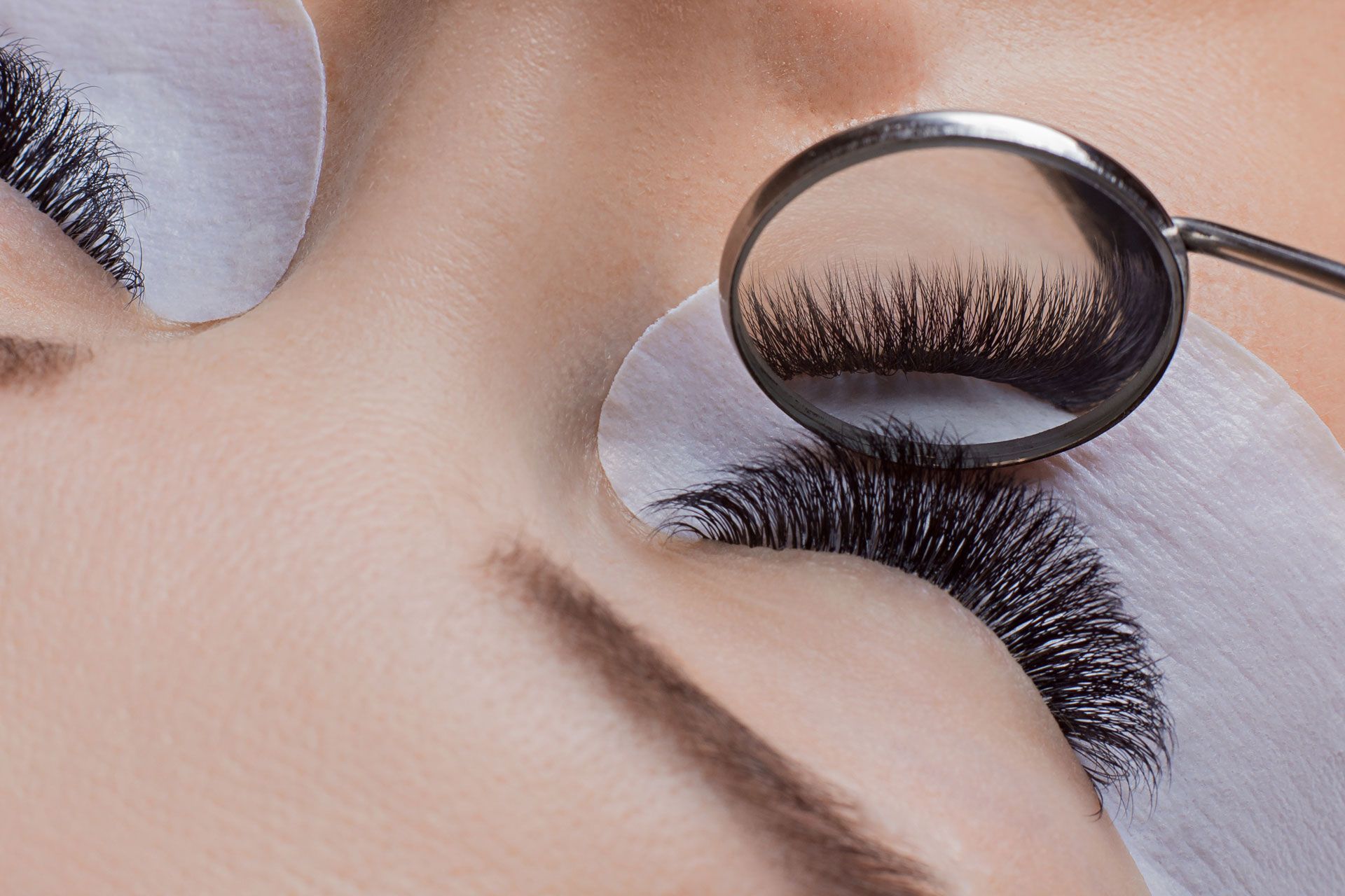 A close up of a woman 's eye with lashes being examined by a mirror