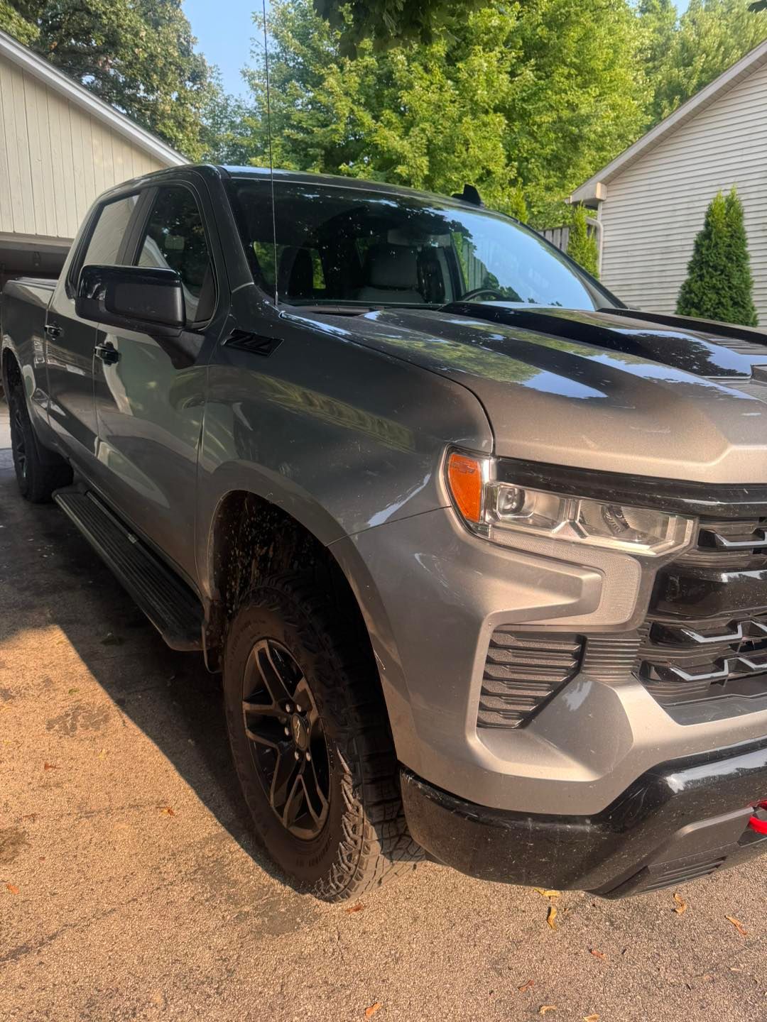 A gray Chevrolet Silverado pickup truck parked on a residential driveway on a sunny day.