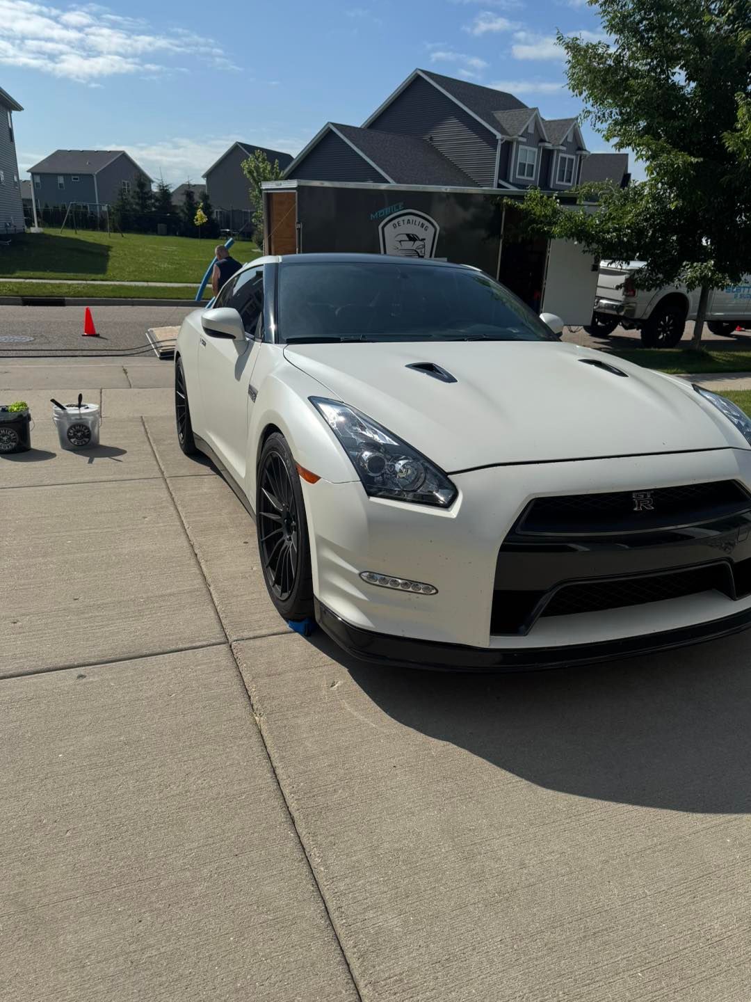 A white Nissan GT-R parked on a residential driveway on a sunny day.