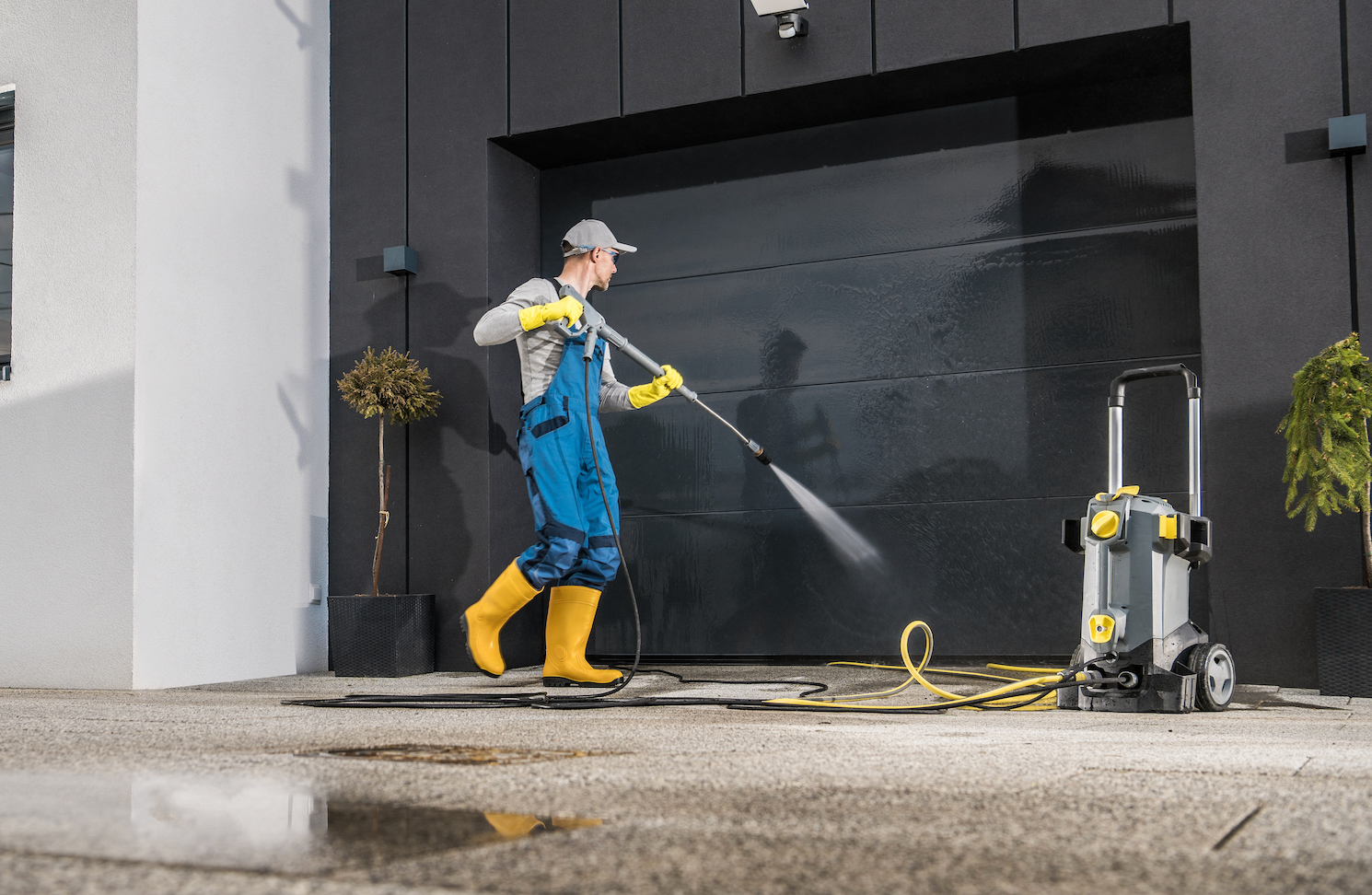 A man is cleaning the sidewalk with a high pressure washer.