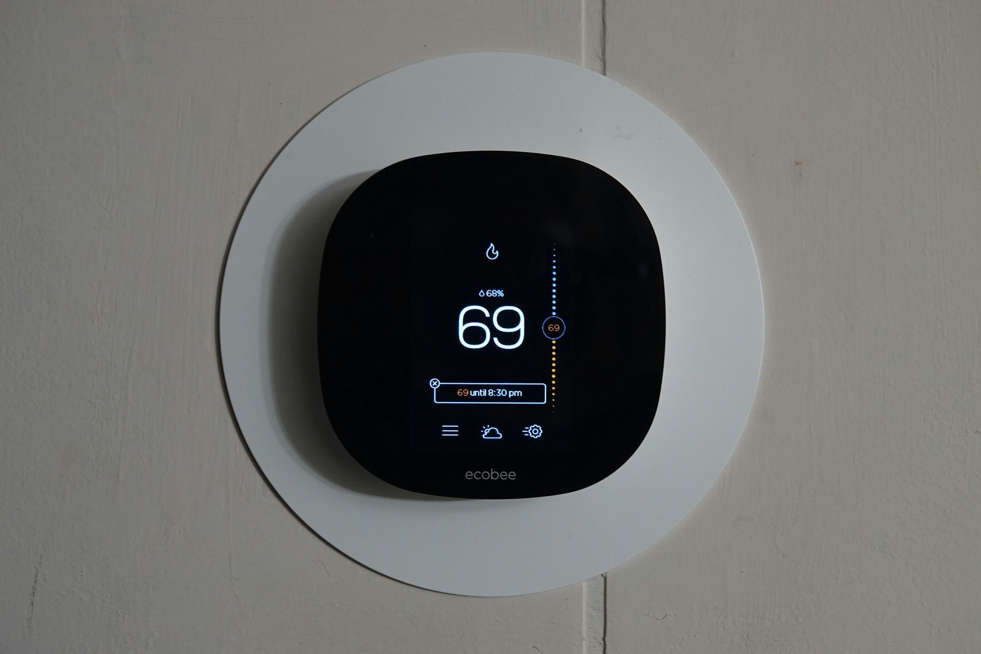 A black thermostat shows the temperature is 69 degrees