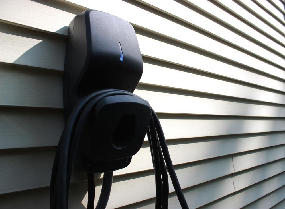 A black device is attached to the side of a house