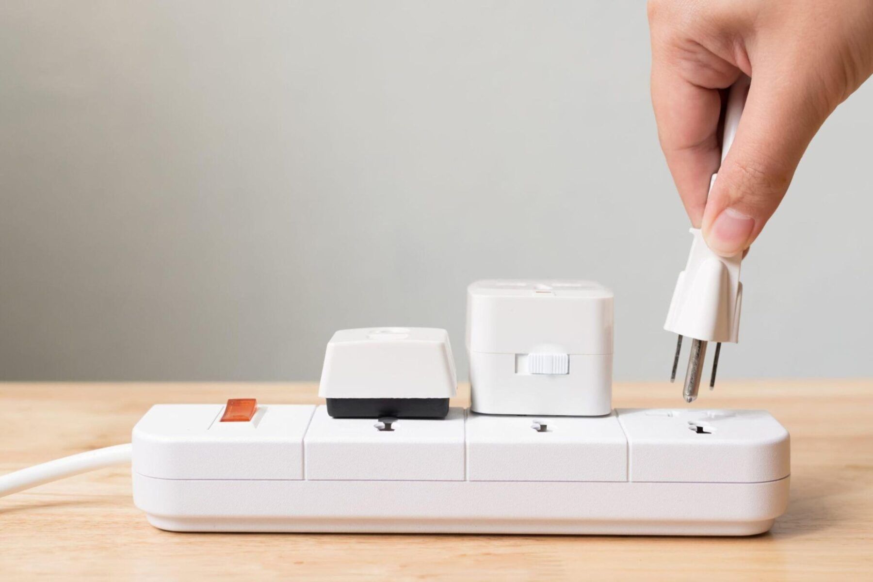 A person is plugging a plug into a power strip.