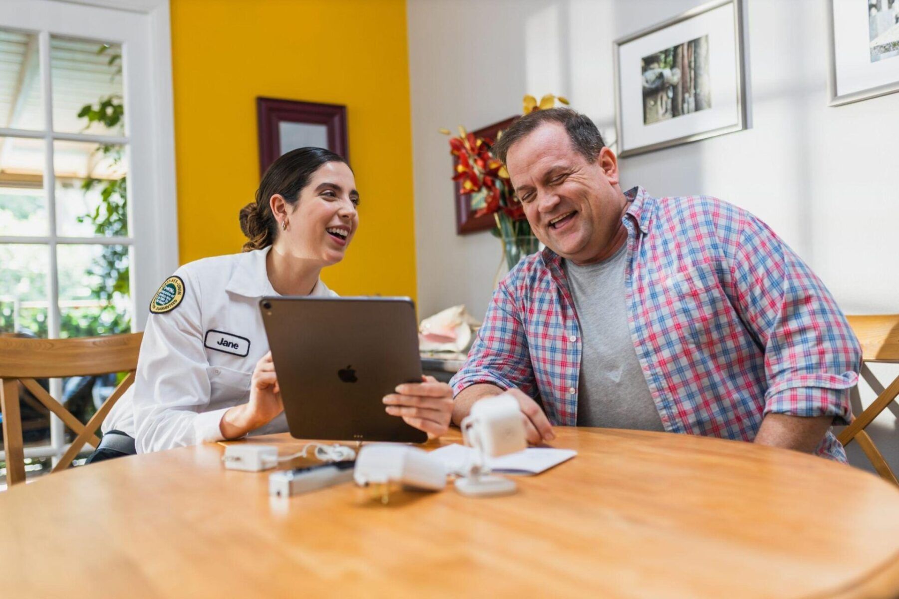 A man and a woman are sitting at a table looking at a tablet.