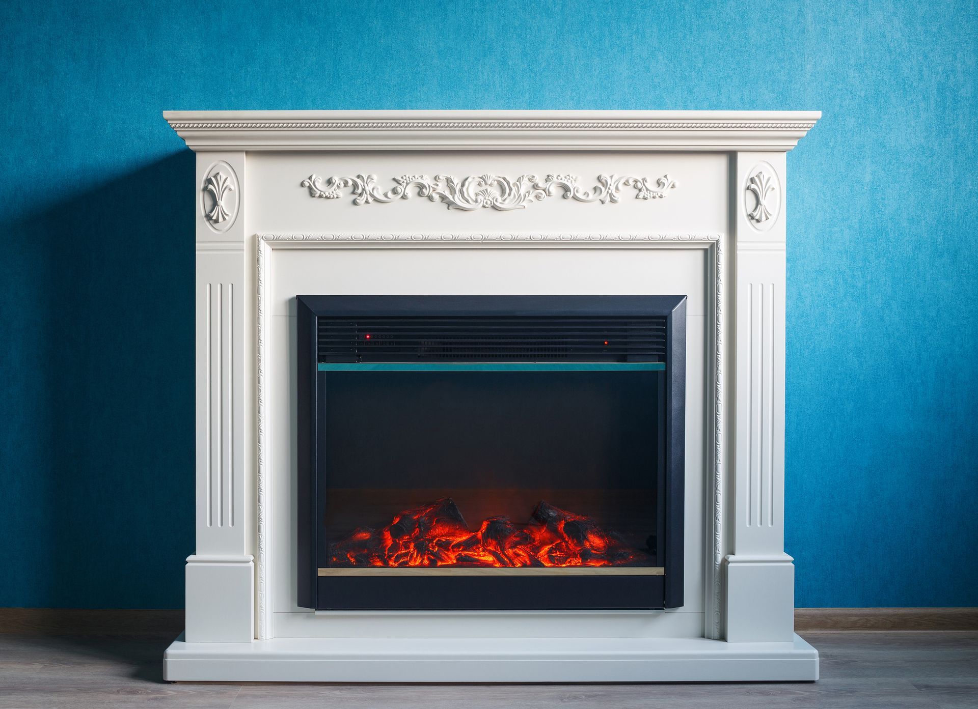 A white electric fireplace is against a blue wall in a living room.