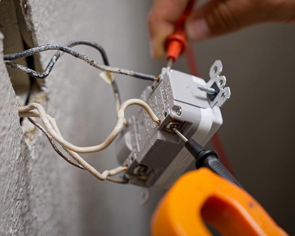 a man in a white shirt with an american flag on his sleeve is working on a electrical outlet