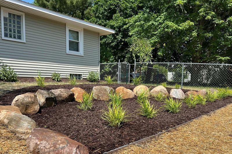 A garden with rocks and plants in front of a house.