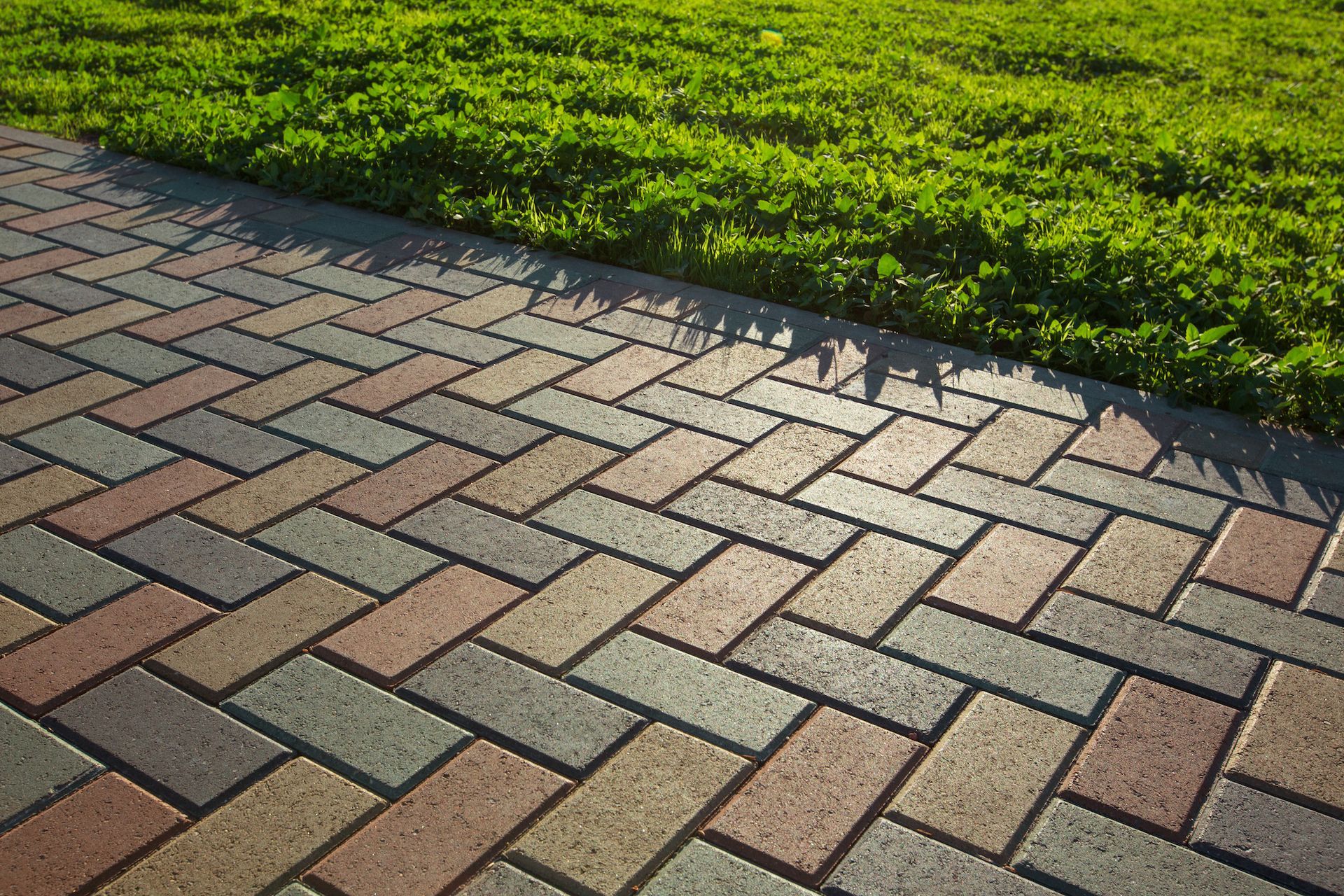 A brick walkway leading to a grassy field.