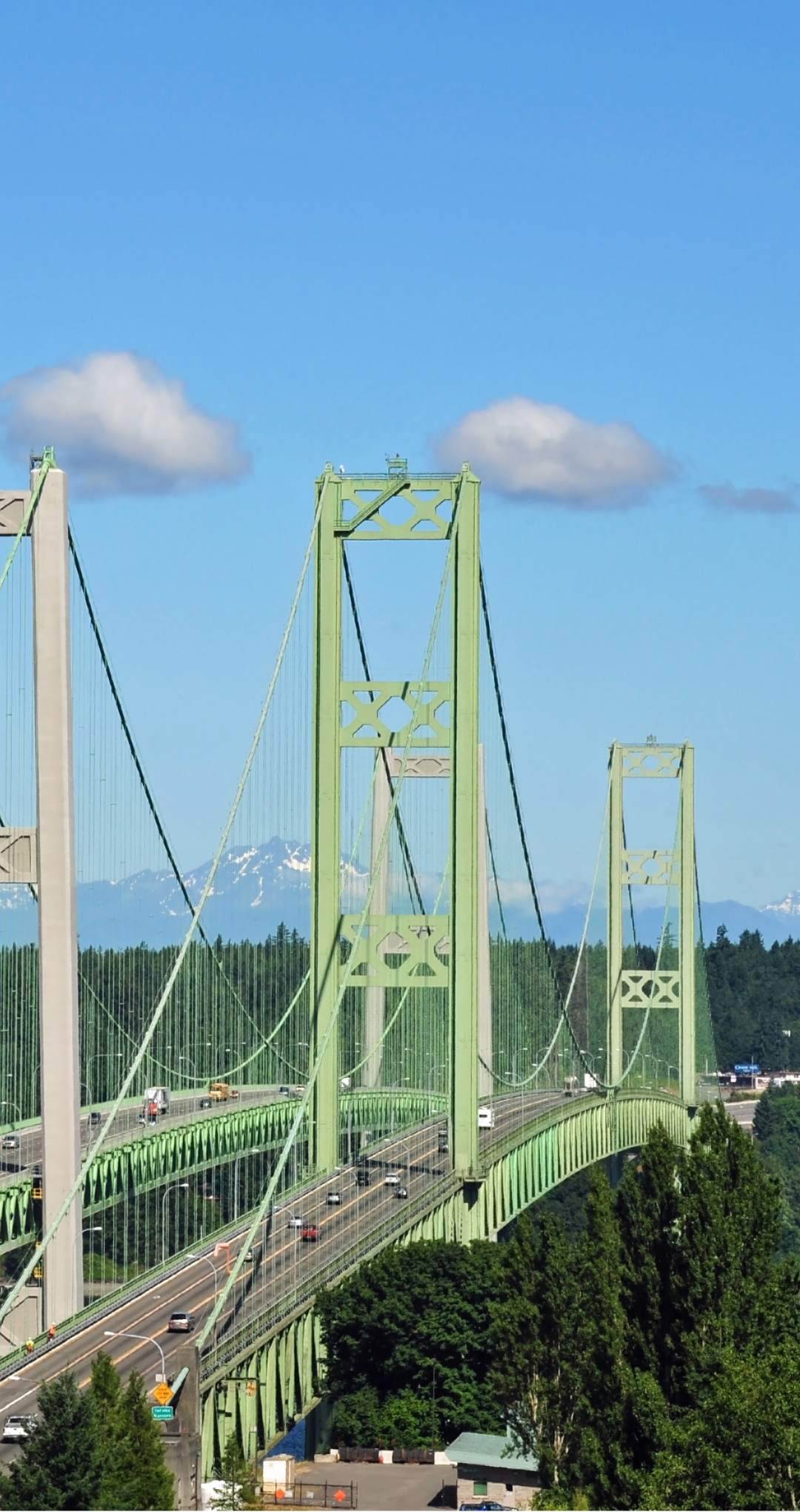 A green bridge with a blue sky and clouds in the background.