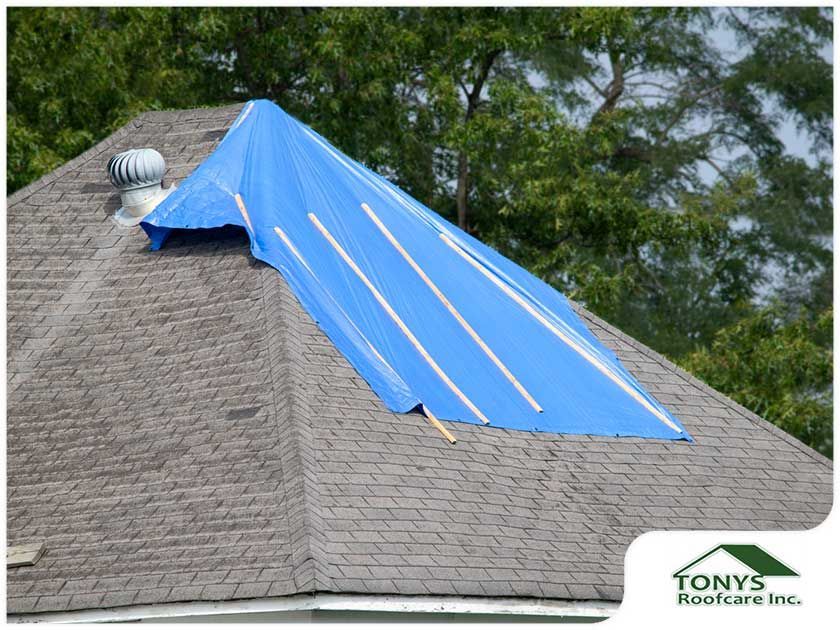 A blue tarp is covering the roof of a house