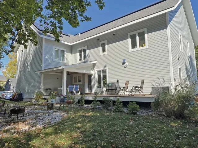 The back of a house with a deck and chairs on it has hardie board siding installed