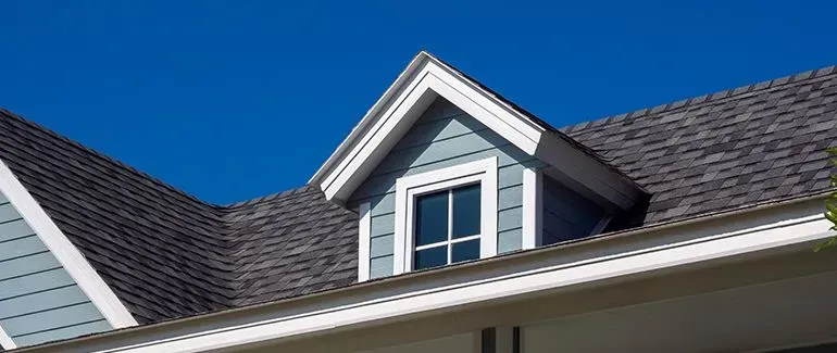 a house with a window on the roof and a blue sky in the background .