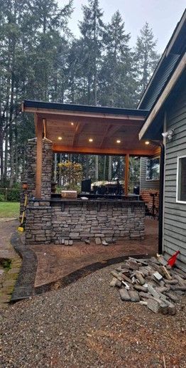 A house with a covered patio in the backyard surrounded by trees.