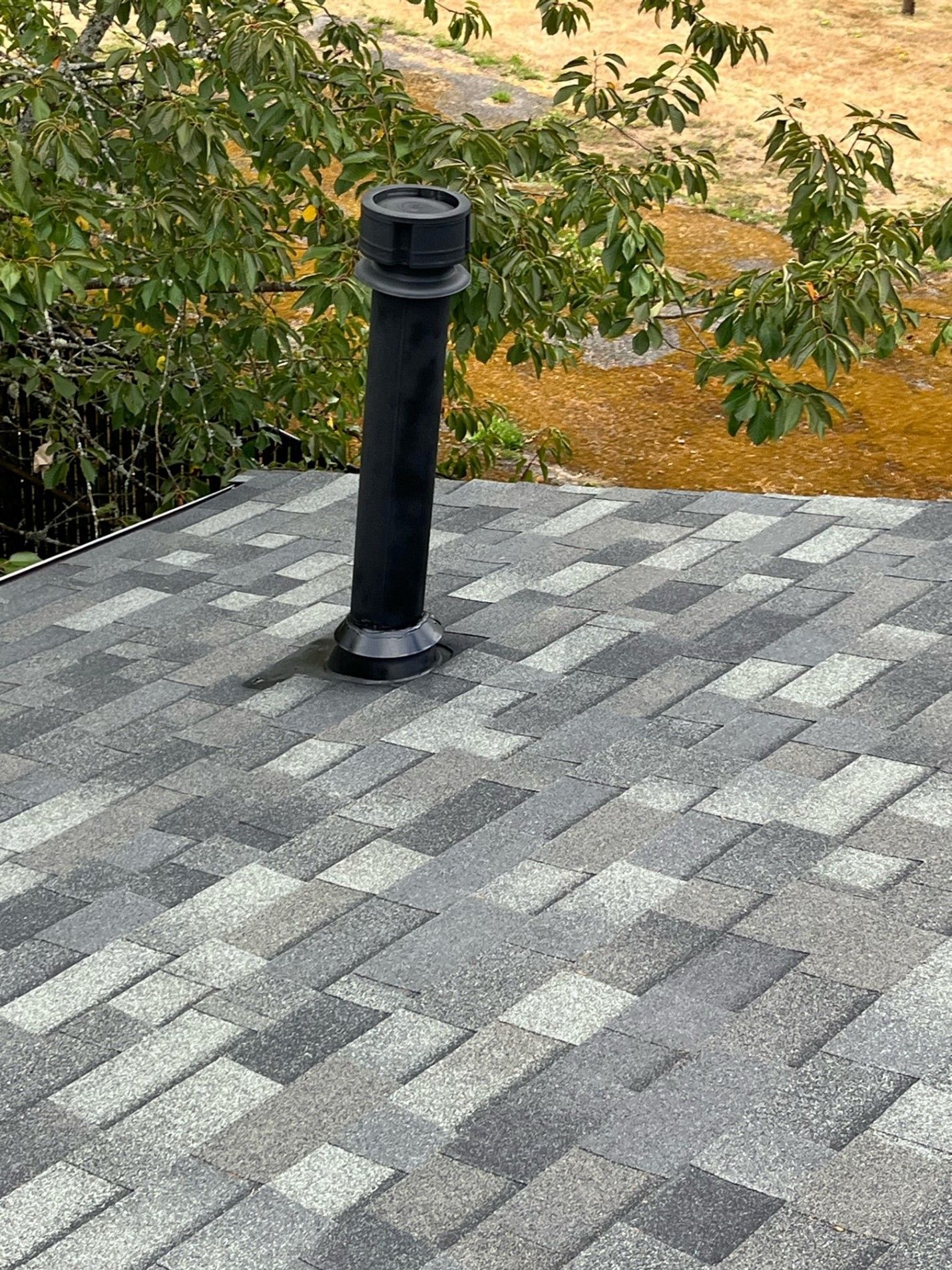 A roof with a chimney on it and a tree in the background.