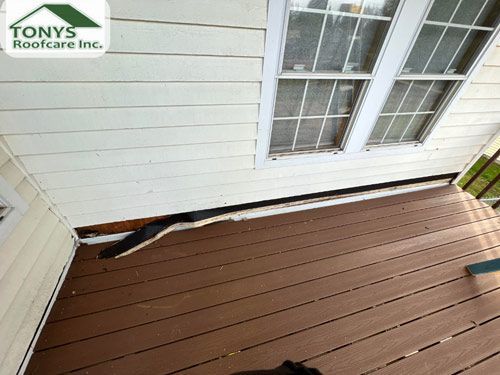 A wooden deck with a window on the side of a house.