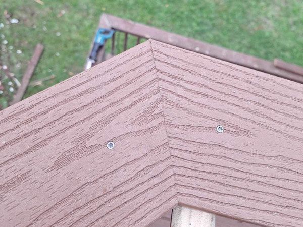 A close up of a wooden deck with screws in it.