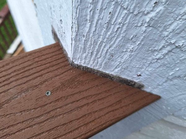 A close up of a wooden deck next to a white wall.