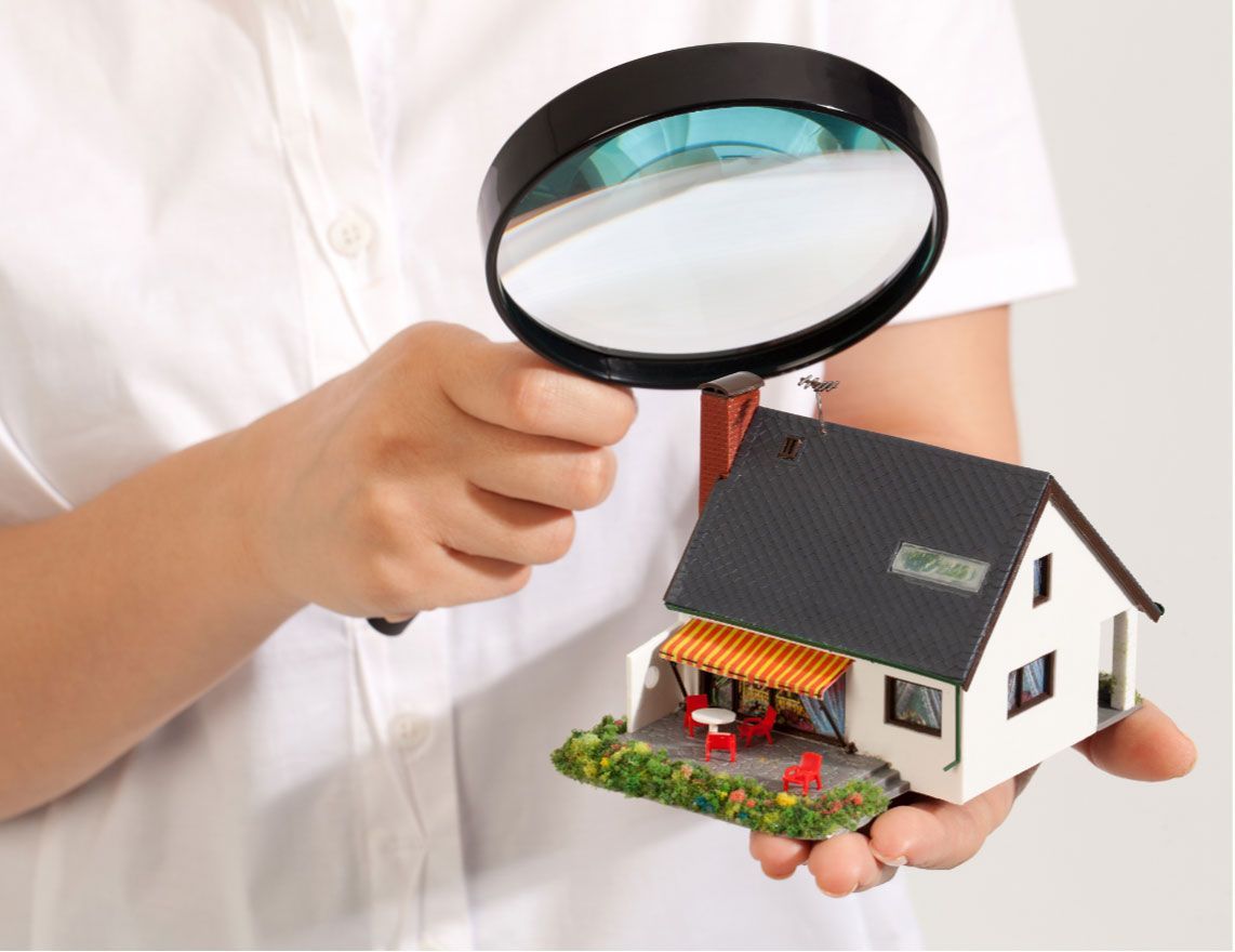 a person is holding a magnifying glass over a model house