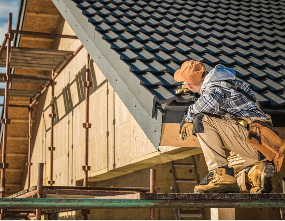 a man is working on the roof of a house under construction .