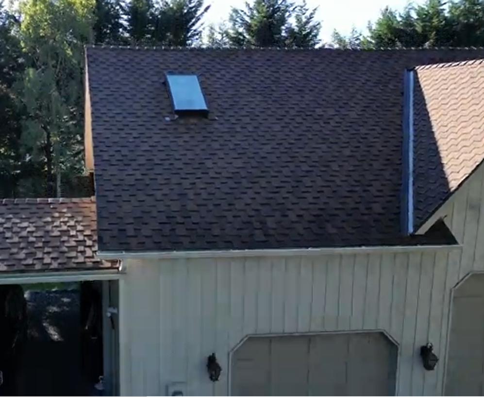 A white house with a brown roof and a skylight