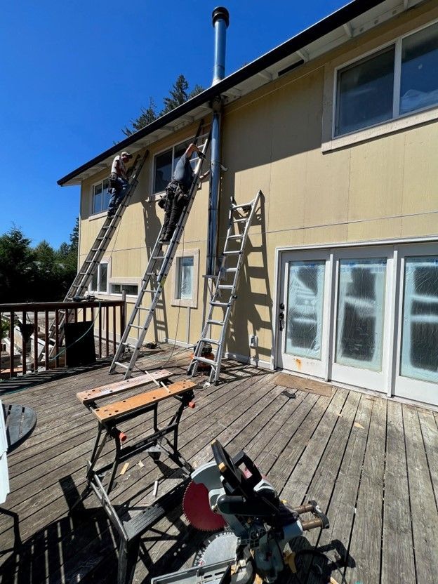 Two men are working on the side of a house