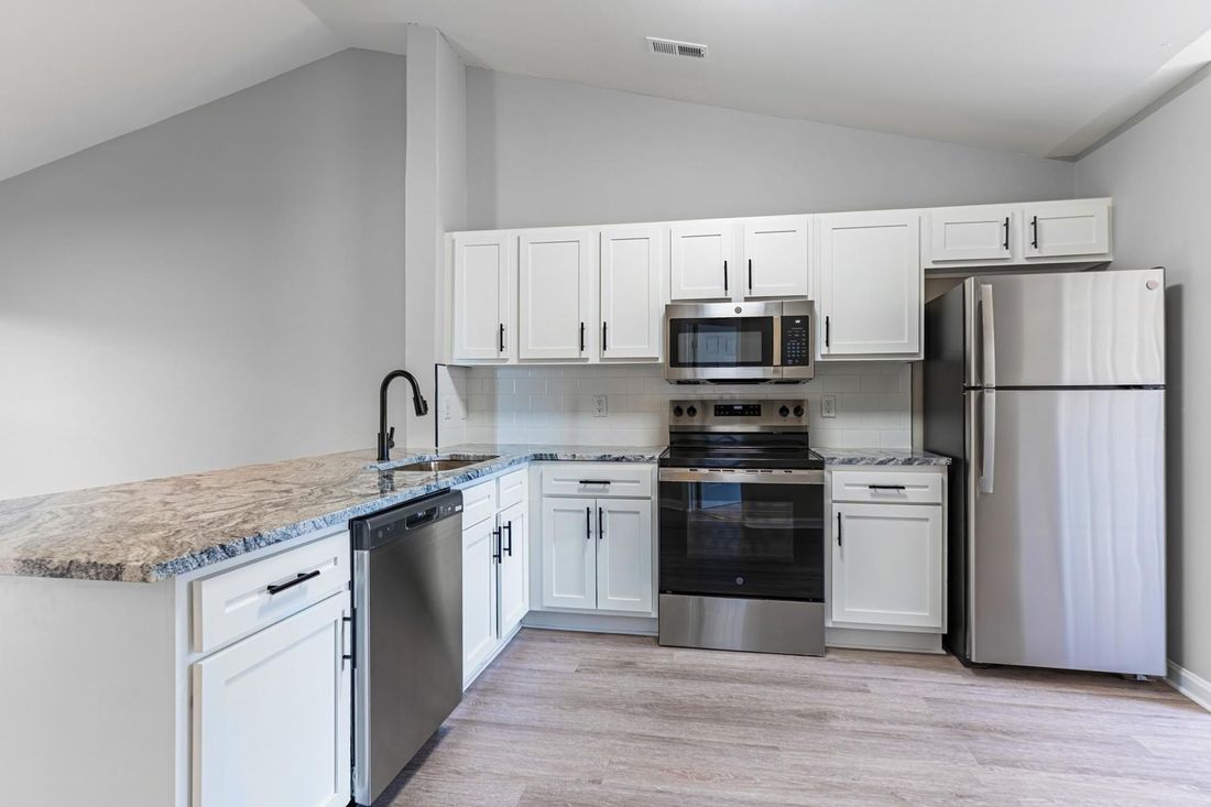 Modern kitchen with white cabinets, stainless steel appliances, and granite countertops.
