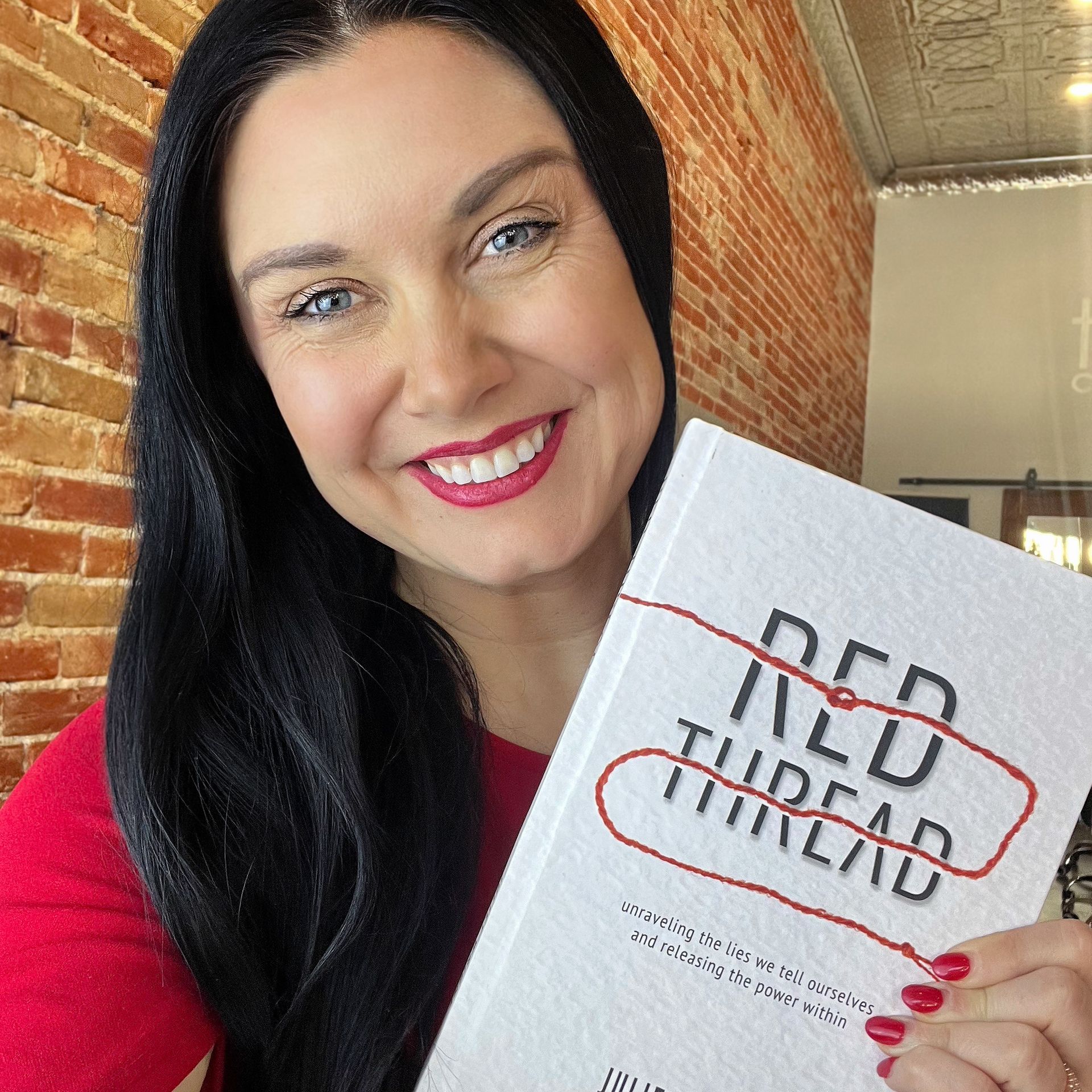 A woman is holding a book titled red thread thread
