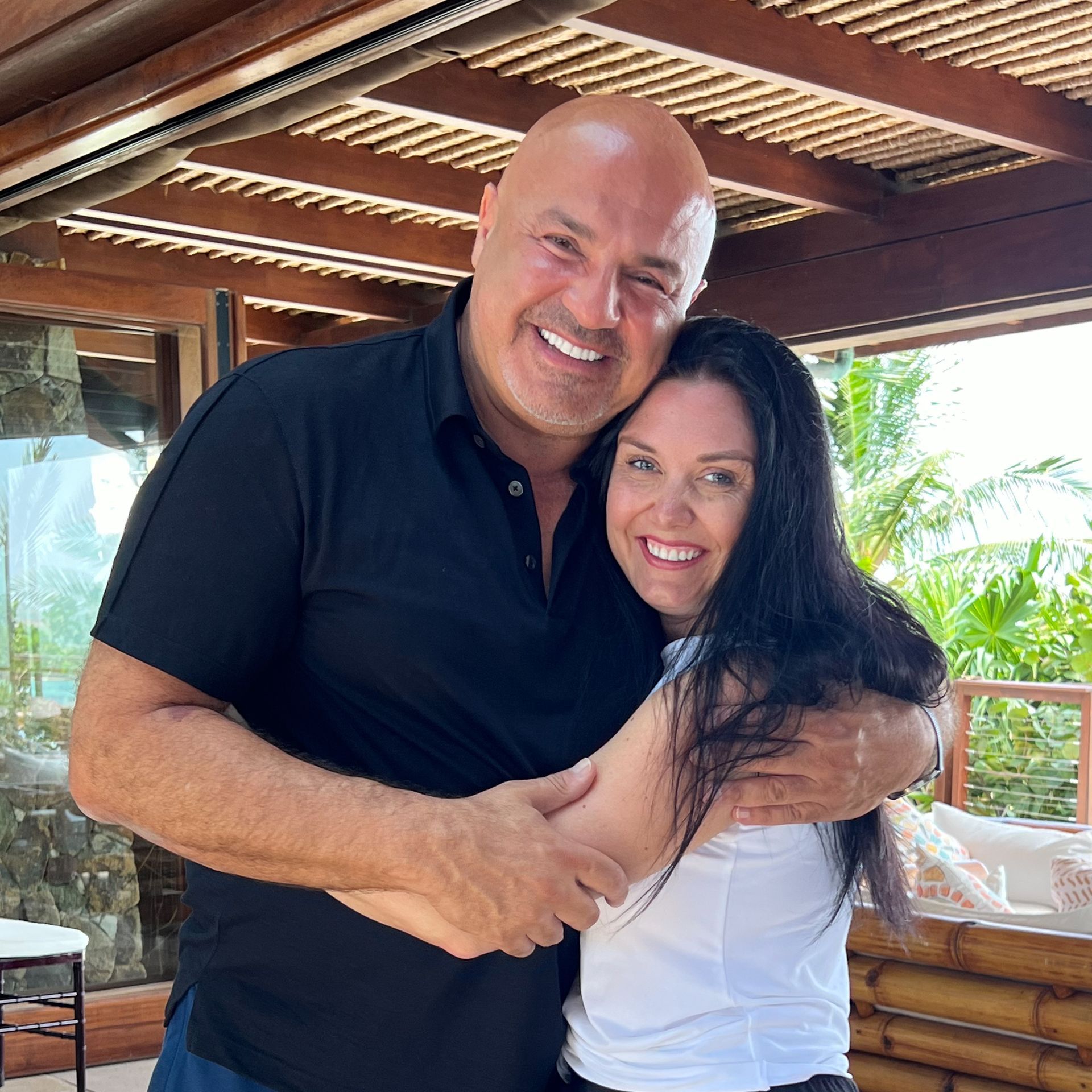 A man and a woman are hugging each other and smiling for the camera.
