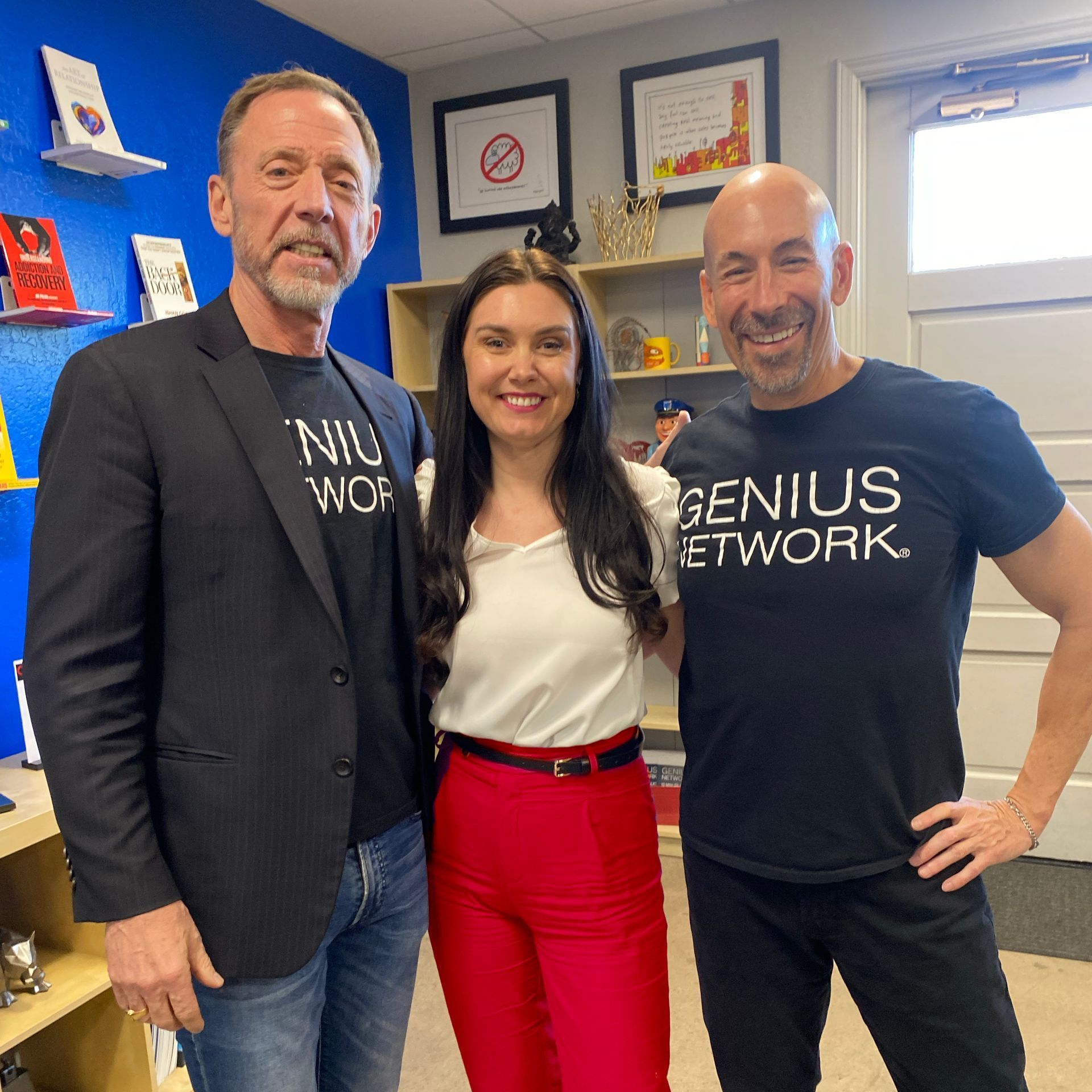 A man wearing a genius network t-shirt poses with two other men