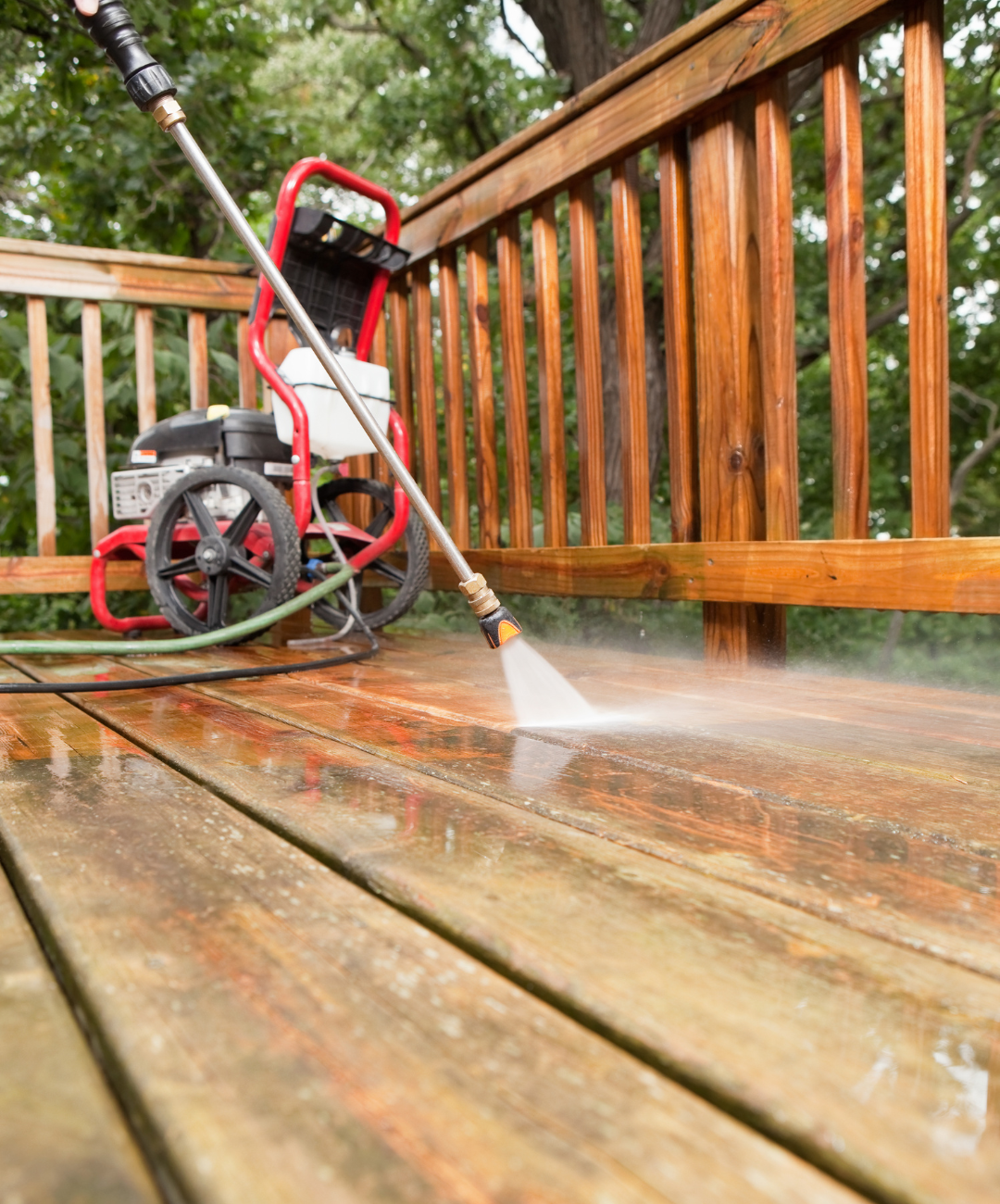 A person is using a pressure washer to clean a wooden deck.