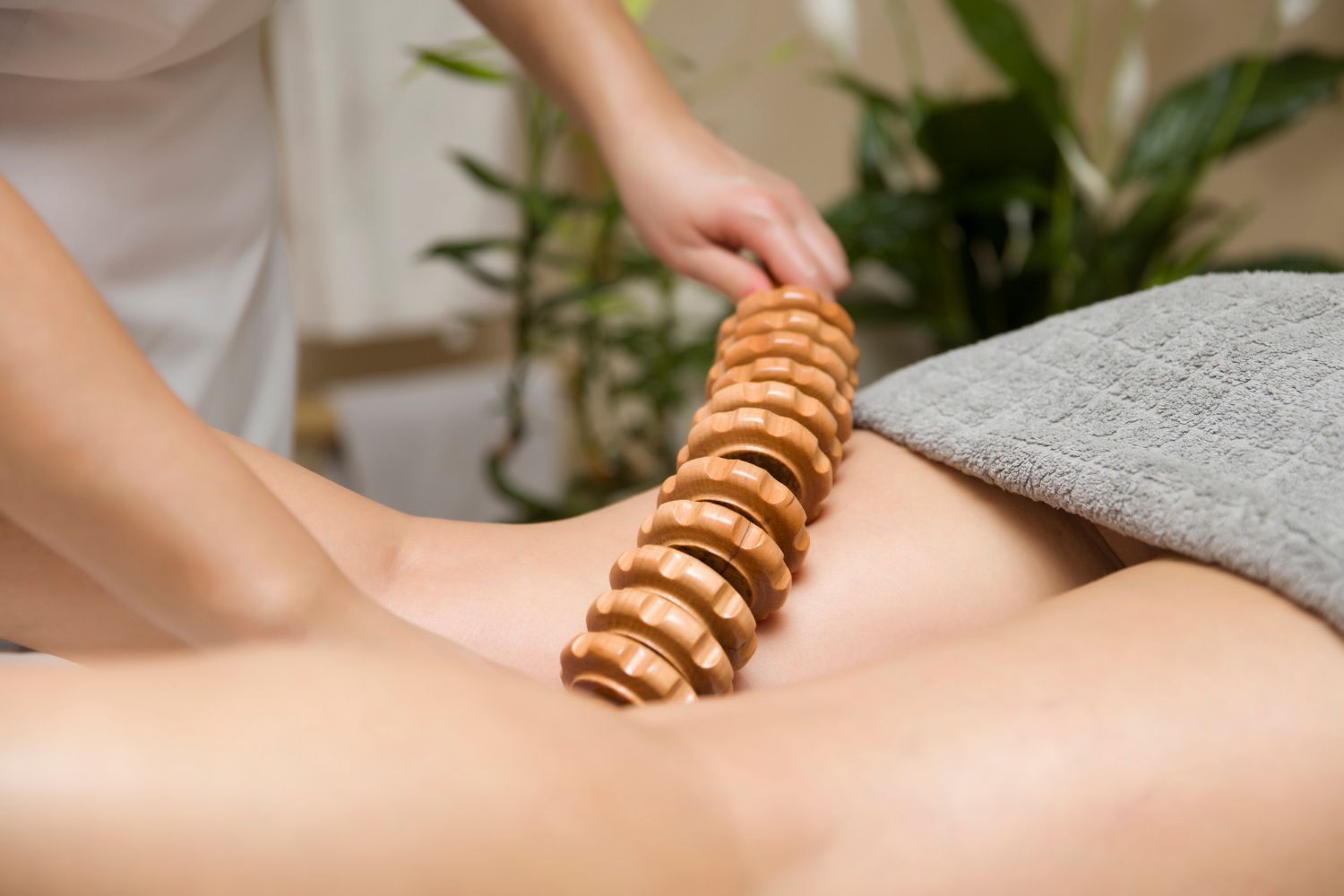 A woman is getting a massage with wooden sticks on her back.