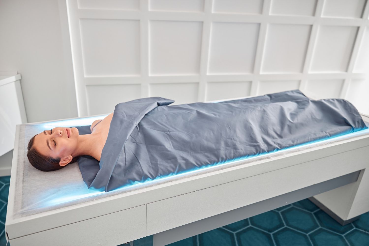 A woman is laying on a bed wrapped in a blanket.