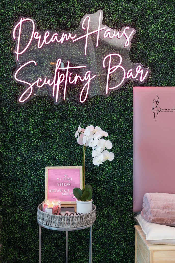 There is a neon sign on the wall that says `` dream house sculpting bar ''.