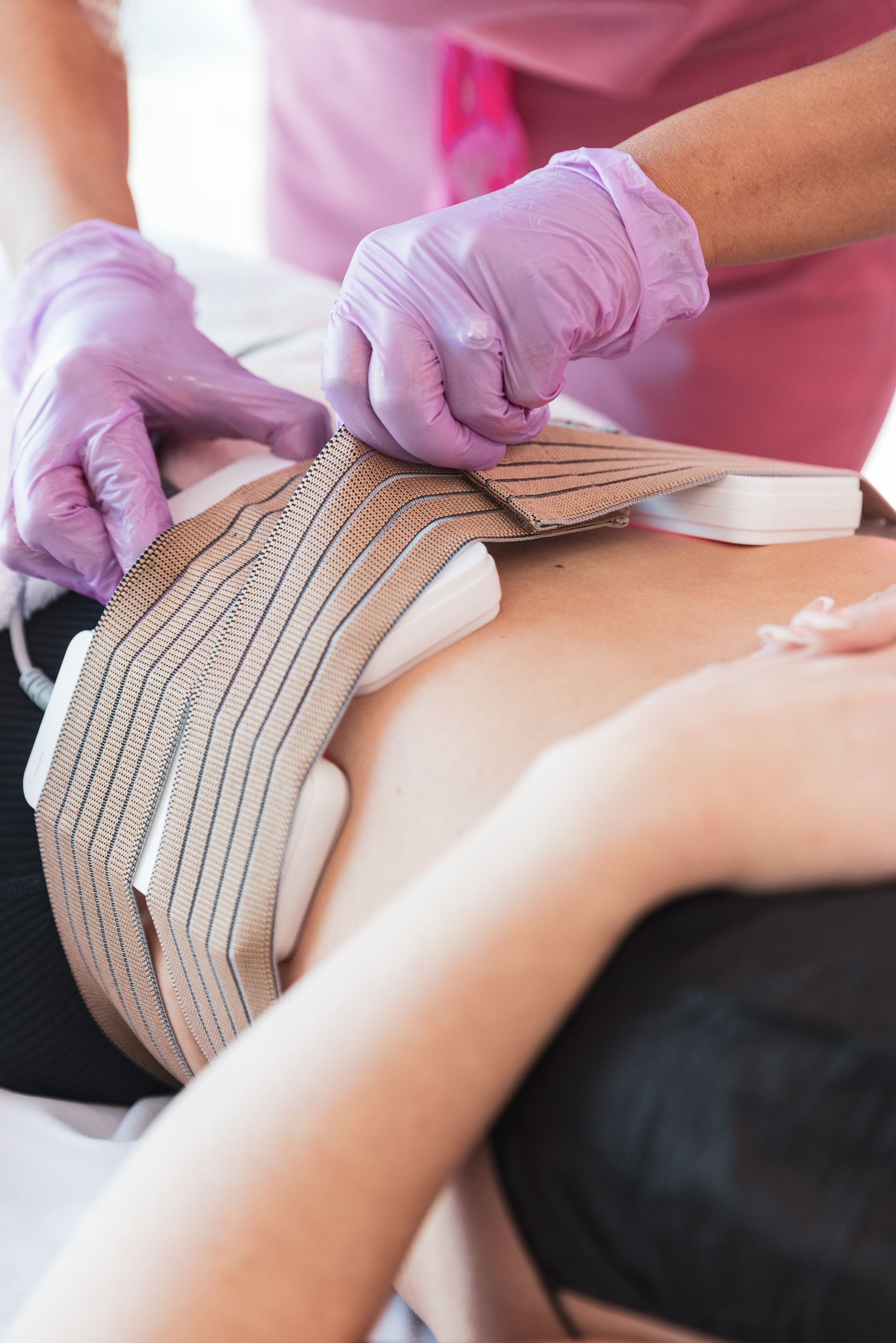A woman wearing purple gloves is getting a treatment on her back.