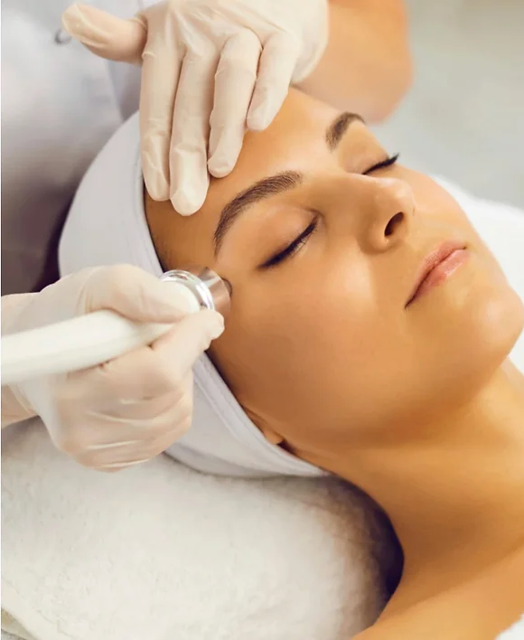 A woman is getting a facial treatment with her eyes closed