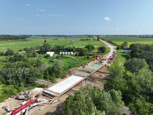 An aerial view of a bridge under construction in the middle of a field.