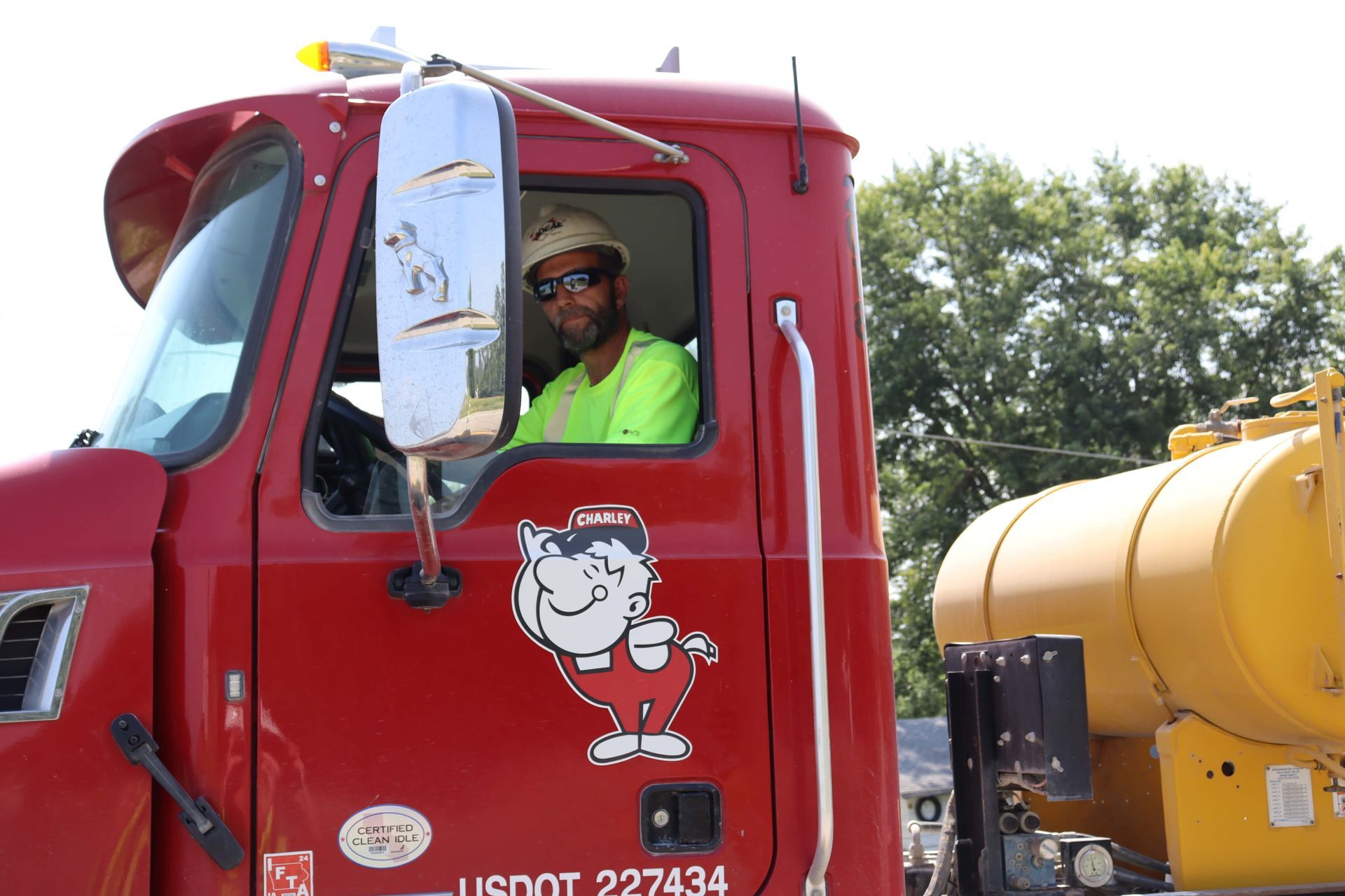 A man is sitting in the driver 's seat of a red truck.