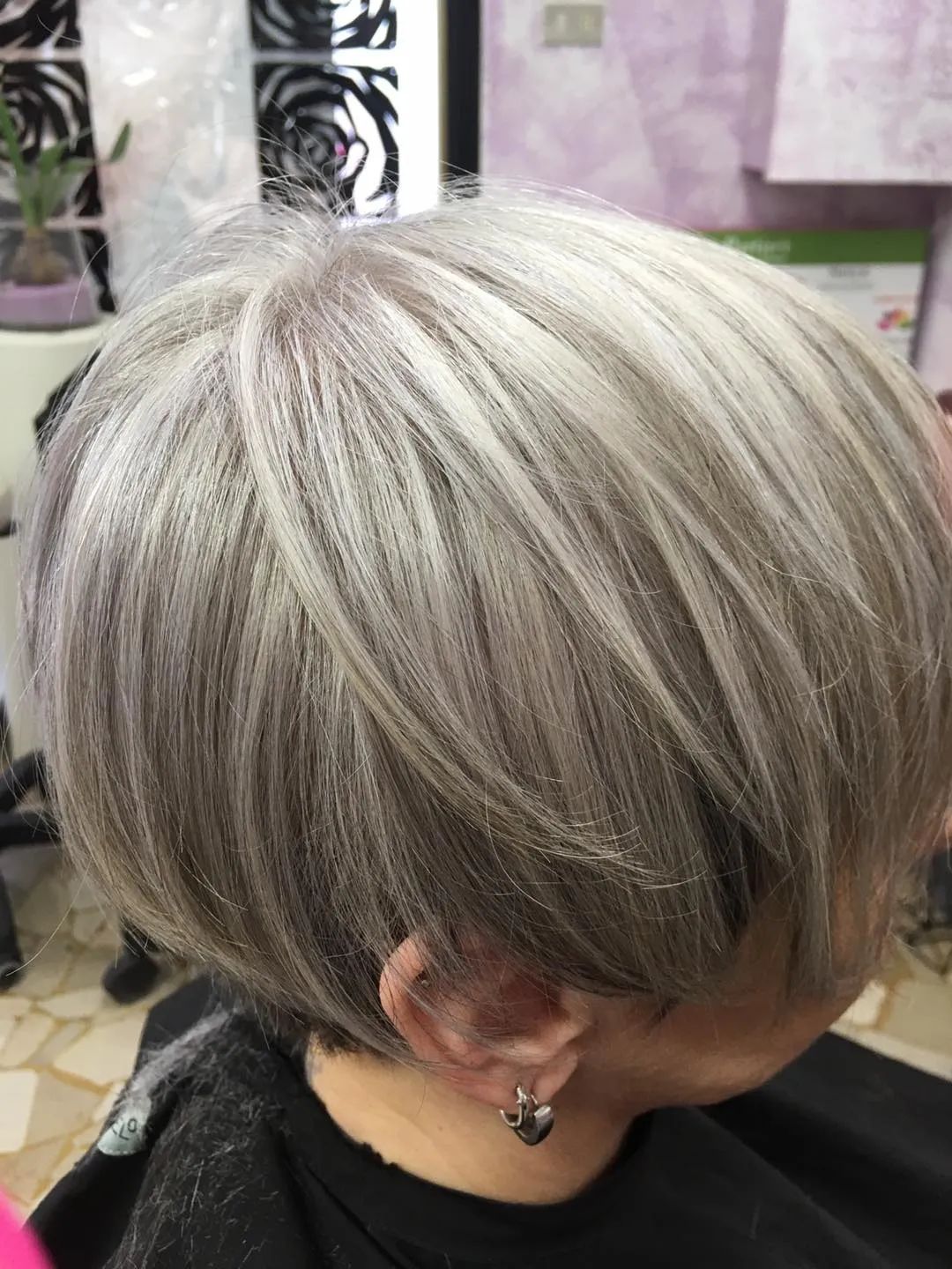 Una donna con corti capelli grigi si sta tagliando i capelli in un salone.