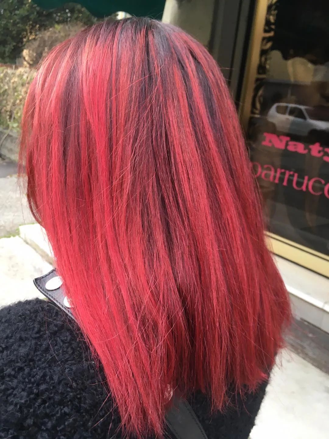 Una donna con i capelli rossi è in piedi davanti a una finestra su cui c'è scritto "nat".