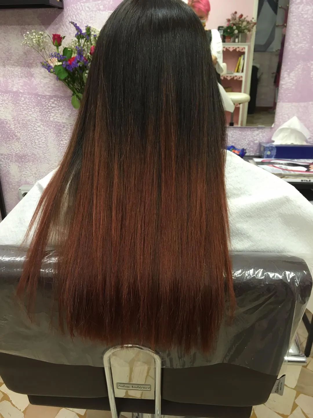 Una donna con i capelli lunghi è seduta su una sedia in un salone.