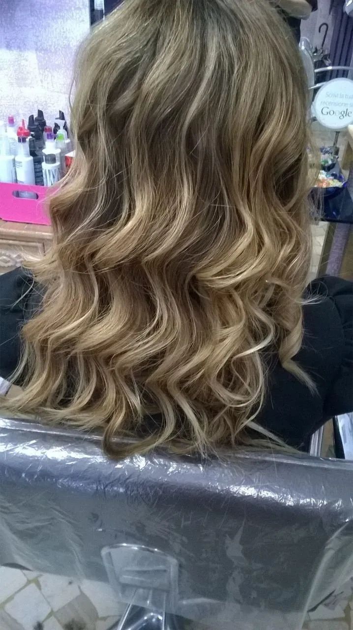 Una donna è seduta su una sedia con i capelli in un salone.