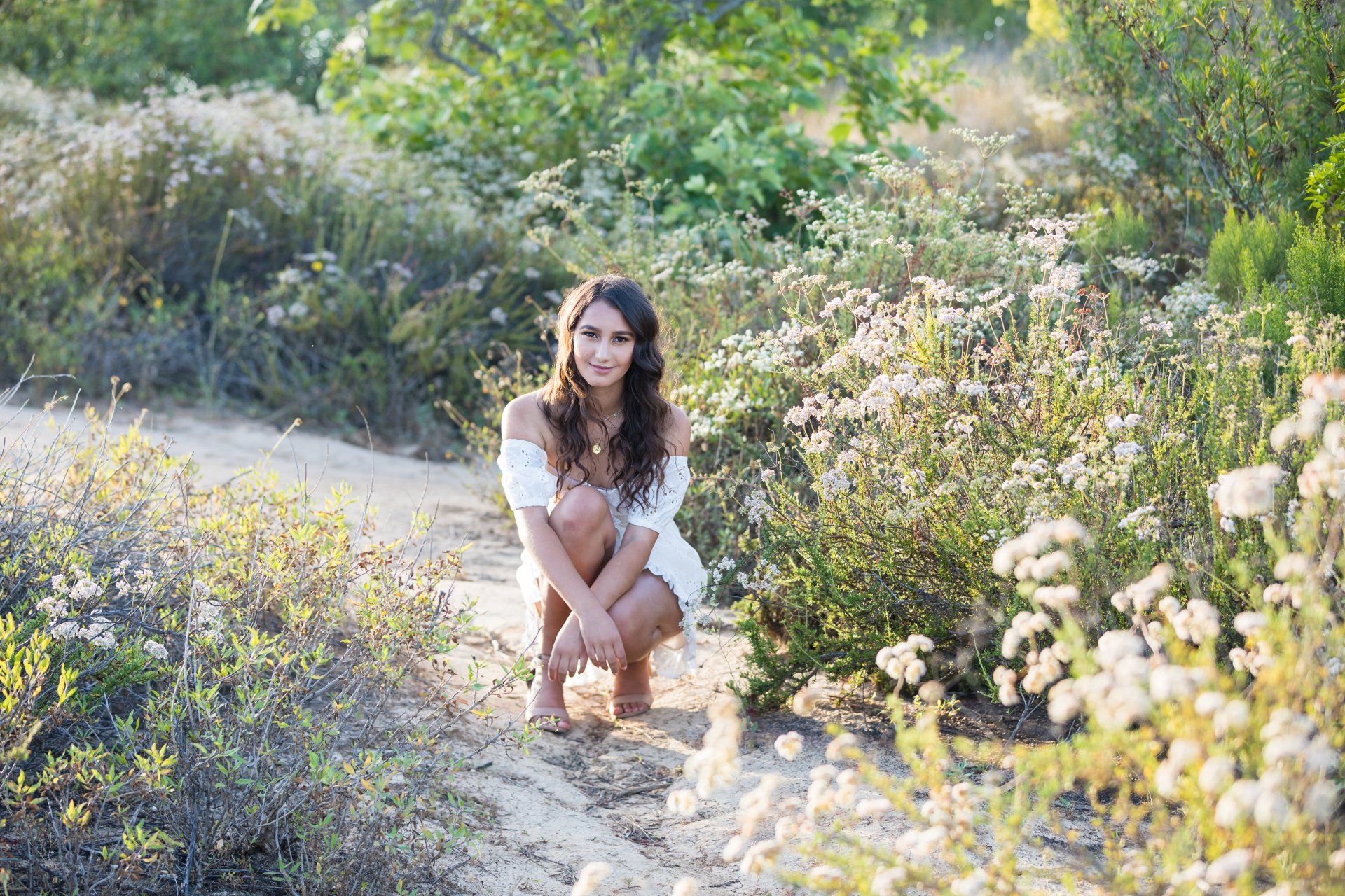 A woman is kneeling down in a field of flowers.