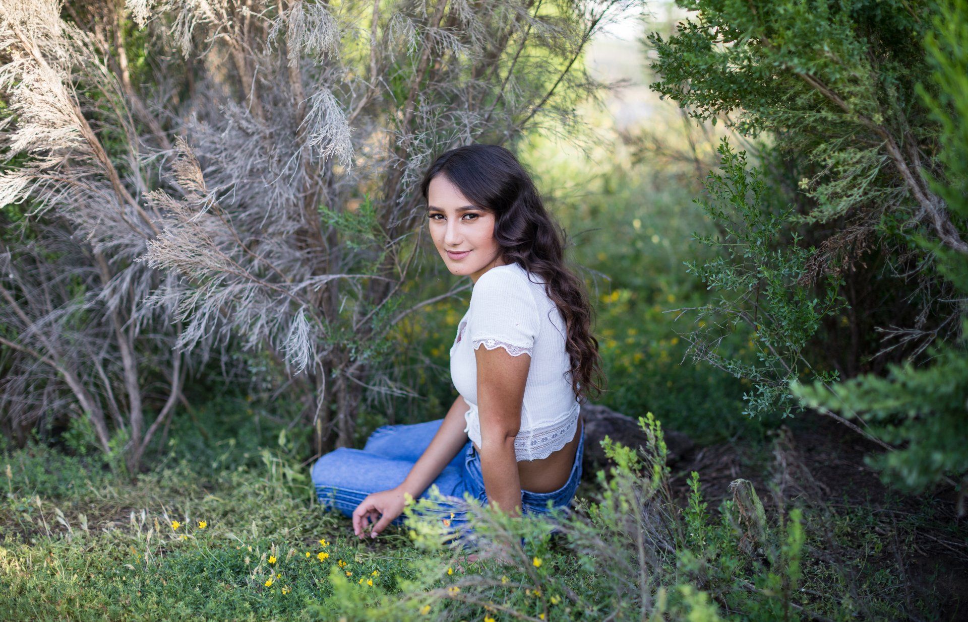 A woman is sitting on a rock in the woods.