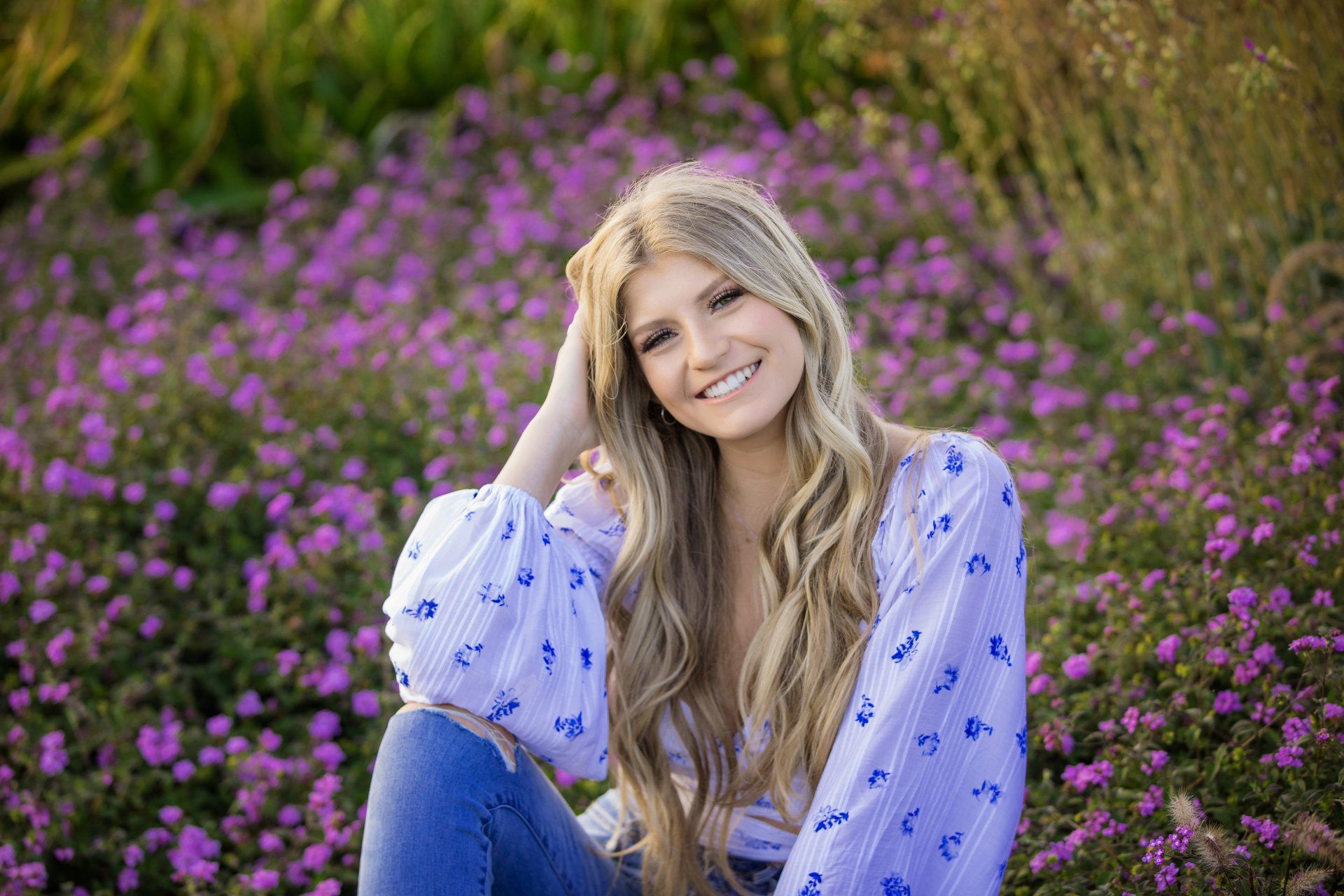 A woman is sitting in a field of purple flowers.