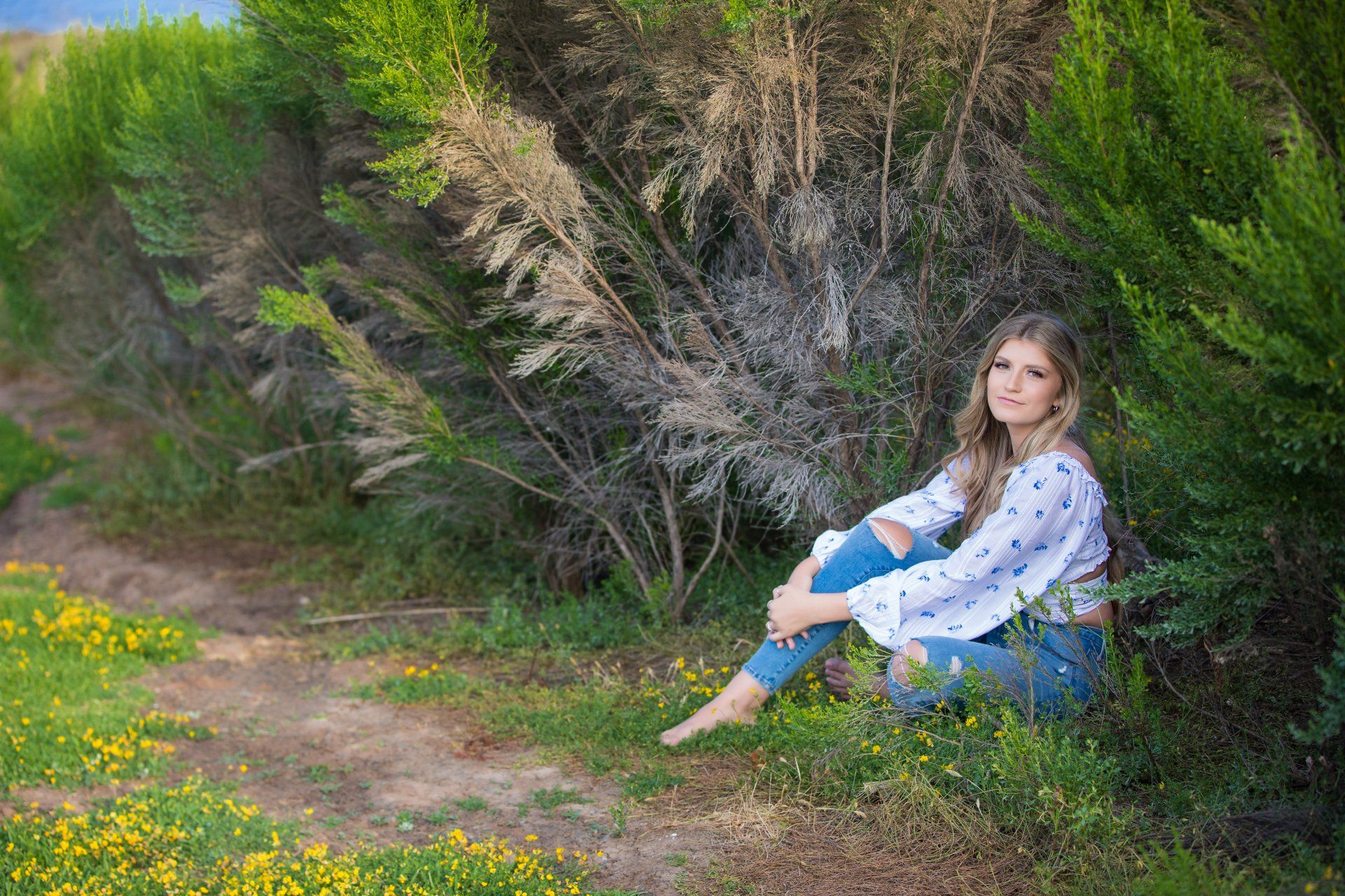 A woman is sitting on the ground in a field of flowers.
